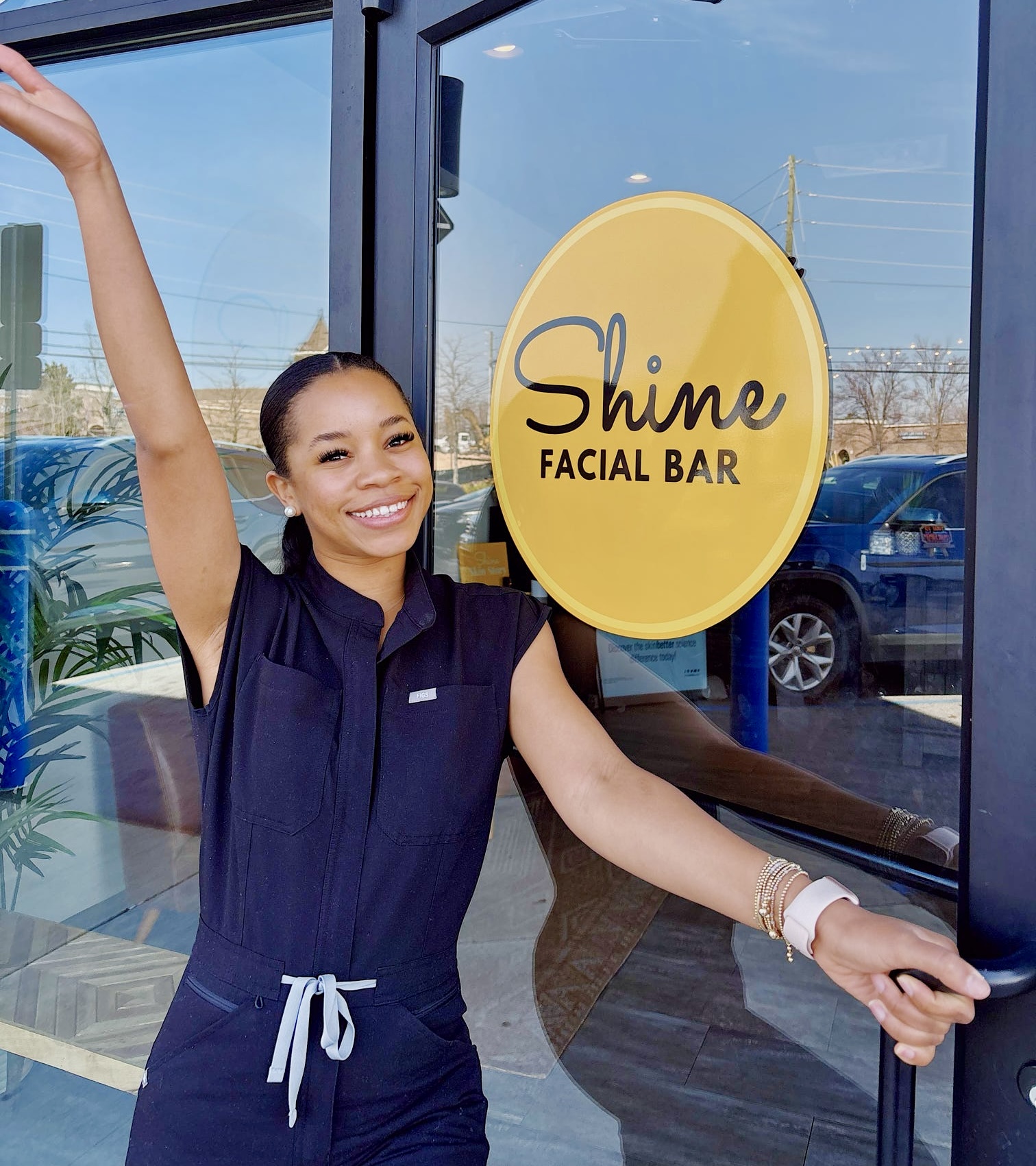 A Shine Auburn esthetician smiling beside the Shine Facial Bar door sign