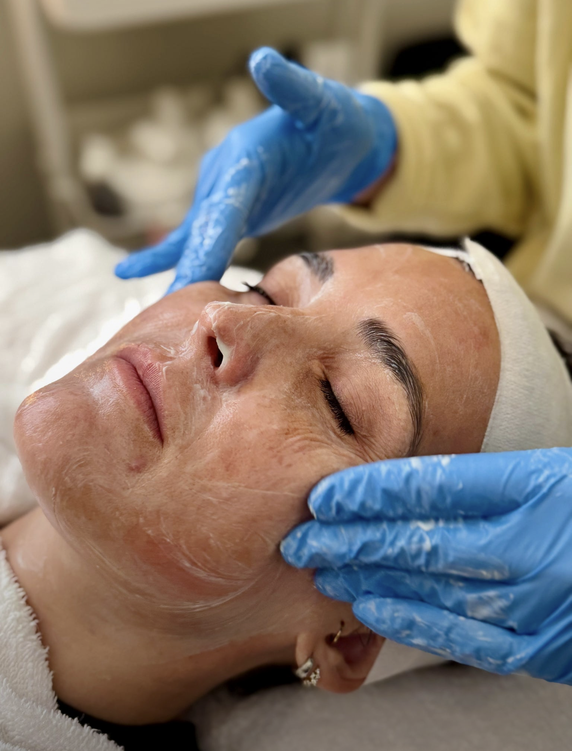 Shine esthetician applying a treatment mask during a facial at the Auburn studio