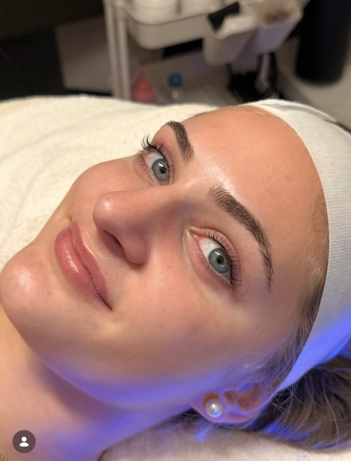 A client relaxing under blue LED light during a facial at Shine Auburn